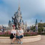 Melanie und Katharina sitzen vor der Statue von Walt Disney vor Cinderella's Castle im Magic Kingdom