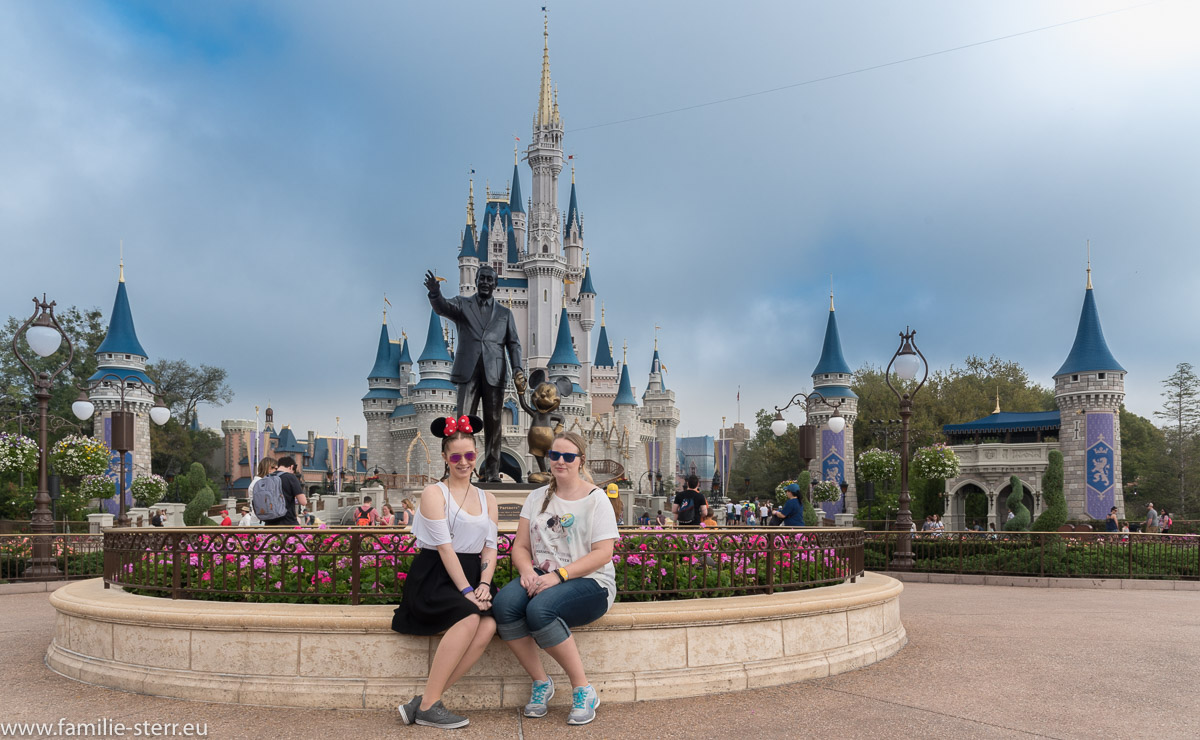 Melanie und Katharina sitzen vor der Statue von Walt Disney vor Cinderella's Castle im Magic Kingdom