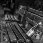 Eine einsame Weinflasche auf einer Reihe von Bänken im Hofgarten München