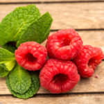 Himbeeren mit Minze auf Holzbrettchen