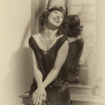 Porträt im Stil der 20er Jahre von Anna vor einem alten Spiegel mit 20er Jahre Kleidchen und Feder
