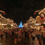 ein Blick über die nächtliche Main Street USA mit unglaublich vielen Menschen und künstlichem Schnee zum beleuchteten Schloss am Ende im Magic Kingdom Themenpark