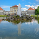 Brunnen vor dem Schloss Nymphenburg vor blau-weißem Himmel