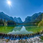 Die Berge am Rand des Toblacher Sees spiegeln sich im grünen Wasser des Sees