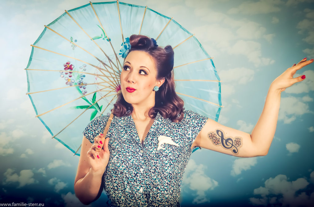 Burlesque - Workshop - junge Frau mit Sonnenschirm vor wolkigem Himmel