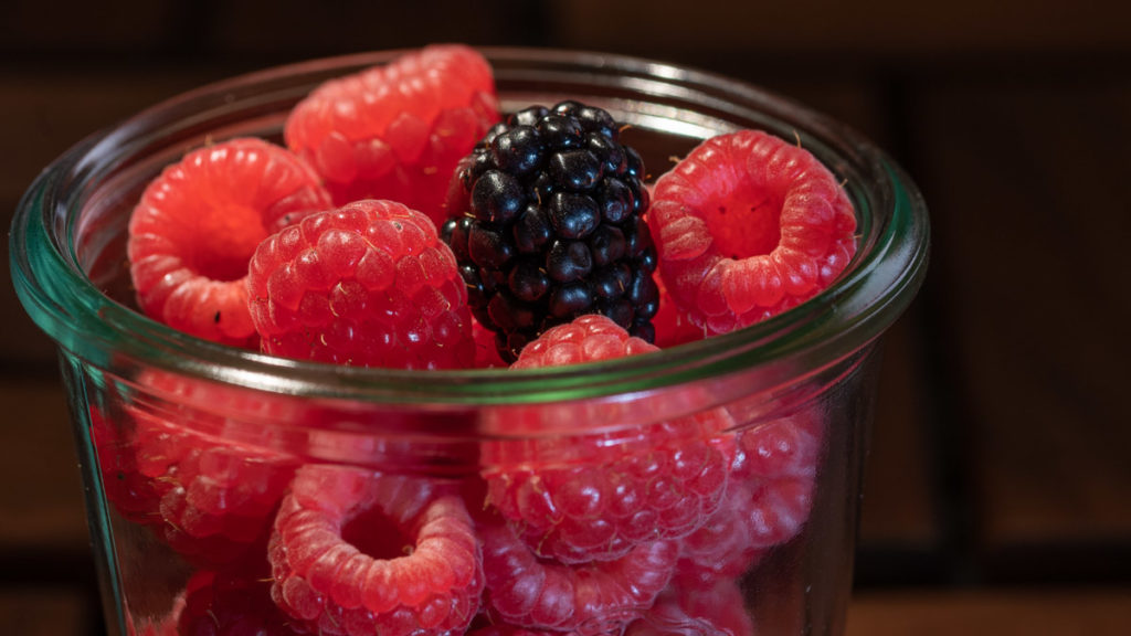 Himbeeren in einem Glas mit einer einzelnen Brombeere