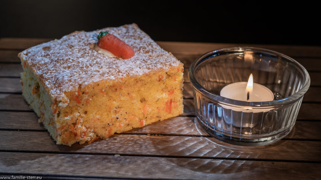 ein Stück Karottenkuchen im Schein eines Teelichts