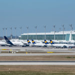 eine Reihe von Lufthansa - Flugzeuge parkt vor dem Satelliten am Terminal 2 am Flughafen München