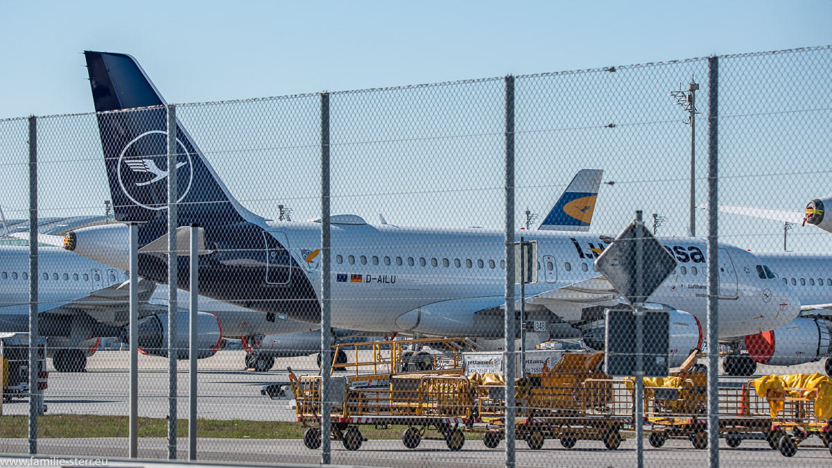 geparkte Flugzeuge der Lufthansa und leere Gepäckwagens auf dem Vorfeld West am Flughafen München