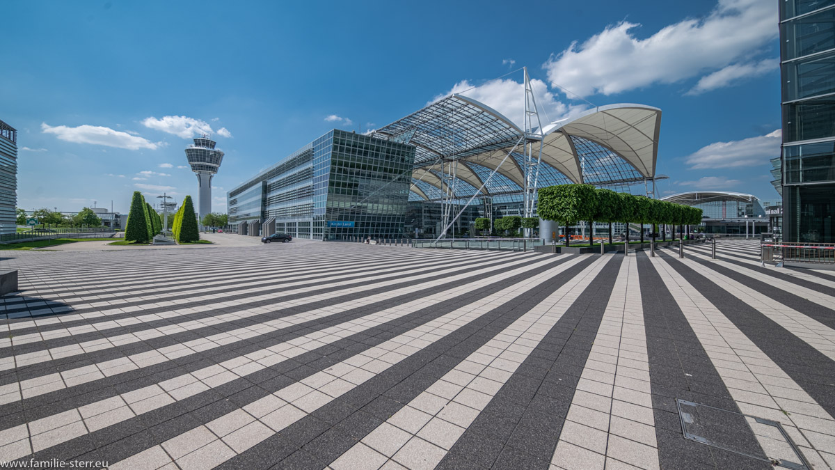 Blick vom Vorplatz des Terminal 2 mit Tower und Munich Airport Center MAC bei strahlendem Himmel