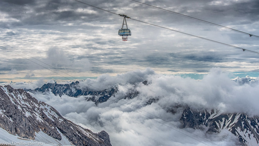 Gondel der Seilbahn von der Zugspitze zum Zugspitzplatt schwebt über tiefhängenden Wolken