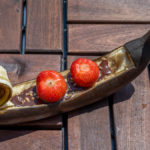 eine gegrillte Schoko - Banana mit Erdbeeren und Haselnüssen in Form einer venezianischen Gondel