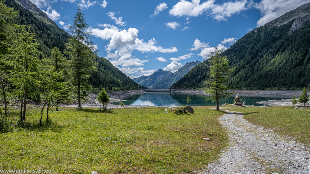 Blick vom nördlichen Ende des Neves - Stausees in Richtung Süden zur Staumauer bei strahlendem weiß-blauem Himmel