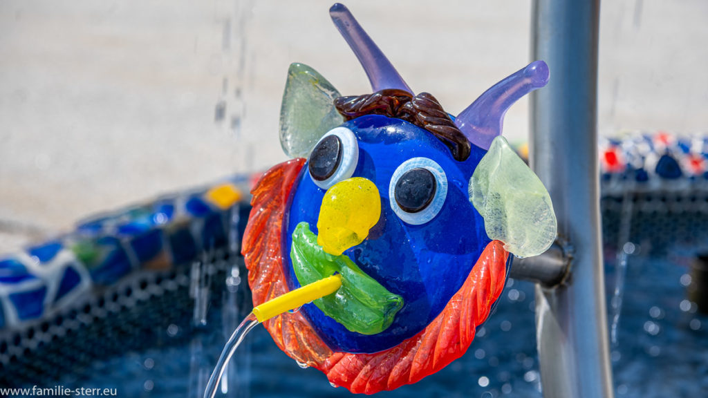 eine gläsernes Gesicht als Wasserspeier an einem Brunnen in der Josua Glaswelt