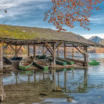 ein altes Bootshaus mit Ruderbooten am herbstlichen Alpsee