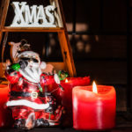 Christbaumfigur in Form eines singenden Weihnachtsmanns vor drei Adventskerzen