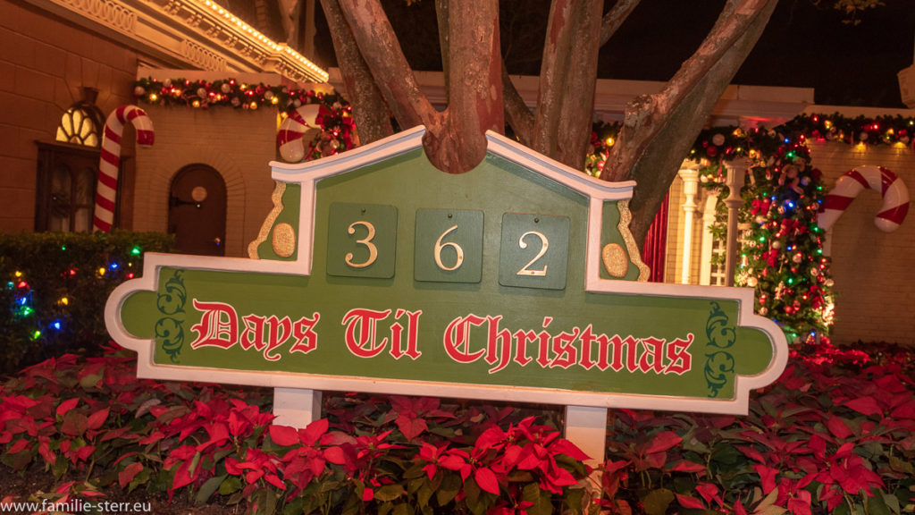 Schild "362 Days till Christmas" in einem Beet mit roten Weihnachtssternen