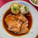 Schweinebraten mit Kartoffelknödel und Semmelknödel auf einem Teller vom Dürnbräu in München