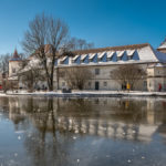 das Schloss Blutenburg spiegelt sich im Eis des zugefrorenen Schlossteichs an einem eiskalten Wintertag