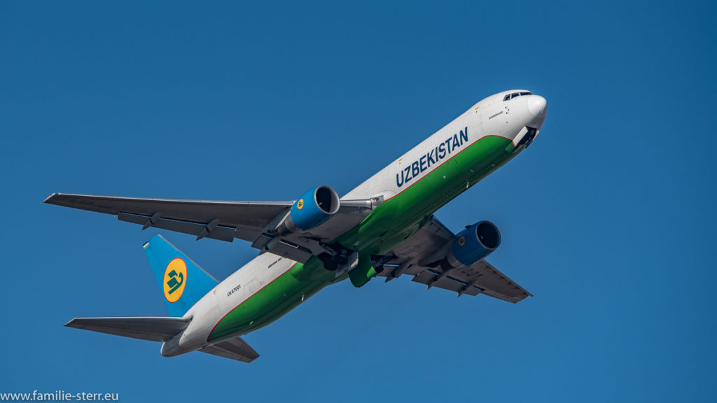 eine Boeing B767 der Uzbekistan Airways im strahlend blauen Himmel über dem Flughafen München