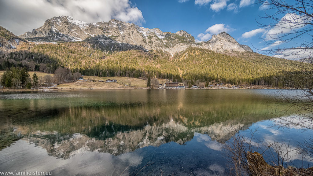 die Berge und der weißblaue Himmel spiegeln sich dem ruhigen Wasser des Hintersees bei Ramsau im Berchtesgadener Land