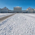 strahlend blauer Himmel über dem schneebedeckten Ehrenhof vor dem Schloss Nymphenburg