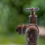 alter Wasserhahn auf der Terrasse überzogen mit rotem Staub von Ziegeln