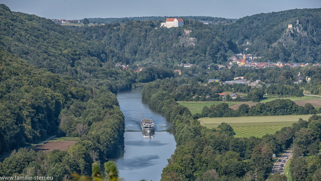 Blick von der Burg Prunn über den Main-Donau-Kanal, im Hintergrund liegt Riedenburg mit dem Schluss Rosenburg, auf dem Kanal fährt ein großer Ausflugsdampfer