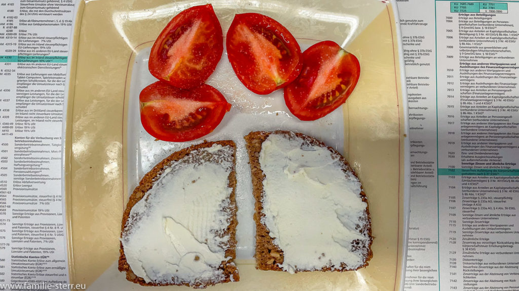 eine Scheibe Vollkornbrot mit Frischkäse und dazu eine aufgeschnittene Tomate