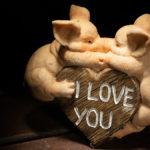 zwei sich küssende Schweine aus Marmor vor einem Herz mit der Aufschrift "I love you"
