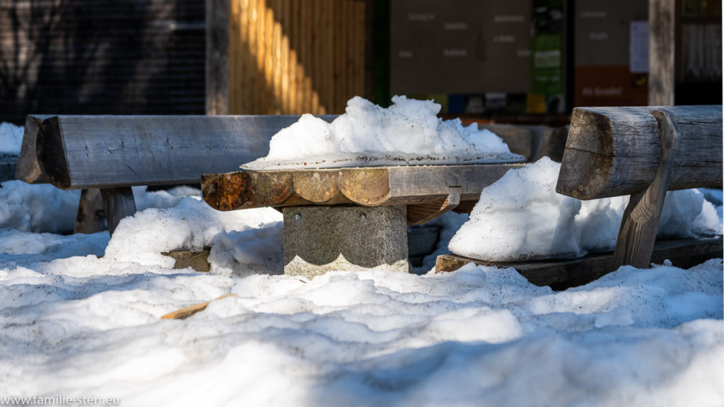 Picknicktisch mit Holzbänken im tiefen Schnee
