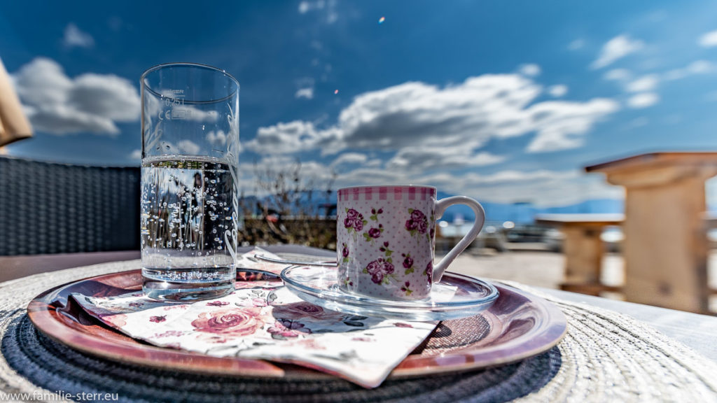 eine Tasse Espresso und ein Mineralwasser auf einem Tisch im Café am Attersee