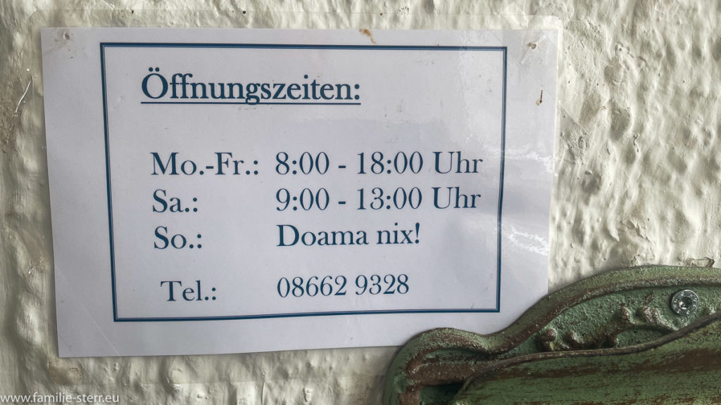 Schild mit Öffnungszeiten und dem Hinweis Sonntag "Doama Nix"