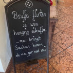 Ein Schild im Biergarten mit der Inschrift "Bsuffa flirten is wia hungrig eikaffa"