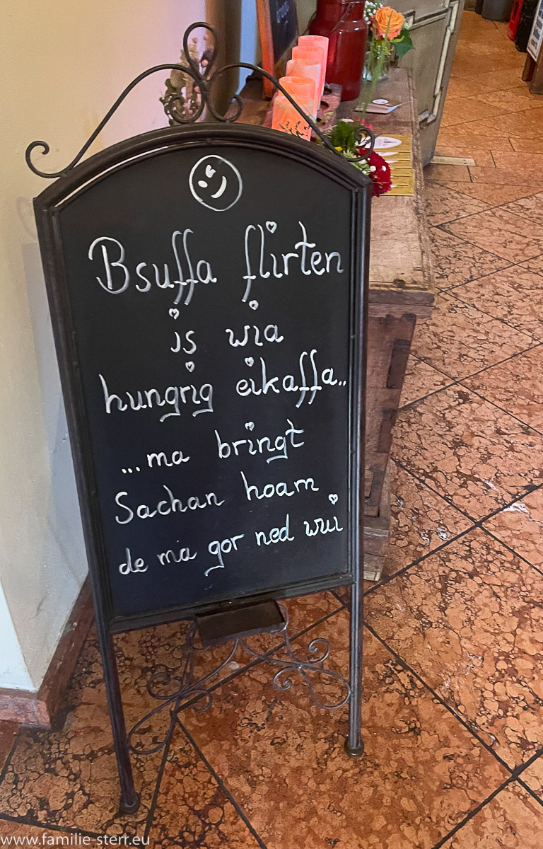 Ein Schild im Biergarten mit der Inschrift "Bsuffa flirten is wia hungrig eikaffa"