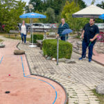 Katharina und Daniel bestaunen einen Schlag von Astrid auf der Bahn beim Minigolf in Prien