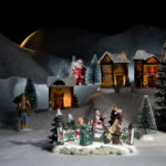 Szene aus unserem Weihnachtsdorf / der Chor singt Weihnachtslieder vor den Häusern