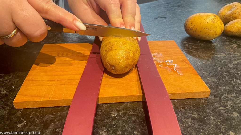 zwischen zwei Silikonstreifen wird eine Kartoffel eingeschnitten