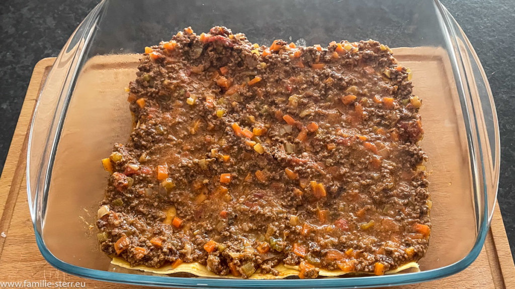eine Schicht Bolognesesoße auf den Lasagnenudeln