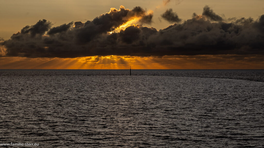 die Sonne wird im Sonnenuntergang über dem Wattenmeer von einer Wolke verdeckt