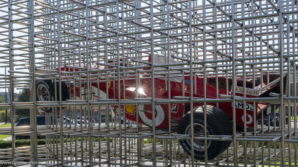 ein Formel - 1 Rennwagen von Ferrari in einem Stahlgestell vor dem Ferarri - Museum