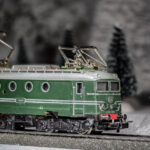 Nikolaus und Knecht Ruprecht stehen im Gleis und blockieren eine Lokomotive, die durch den winterlichen Wald fährt (Modellbahn)