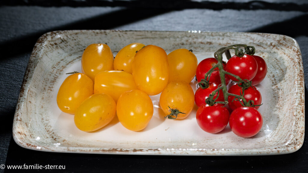 gelbe und rote Cherry - Tomaten auf einem beigen Teller