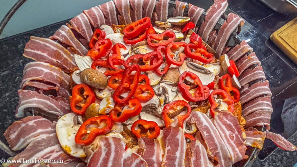 Pilze und Spitzpaprika kommen oben auf die geschichteten Steaks in den Dutch Oven