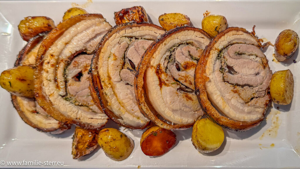Porchetta aufgeschnitten in Tranchen mit Rosmarinkartoffeln