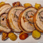 Porchetta aufgeschnitten in Tranchen mit Rosmarinkartoffeln