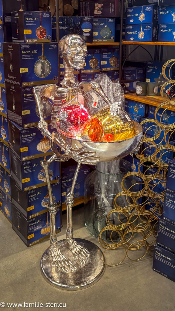 Skelettfigur mit Tablett voller großer Christbaumkugeln