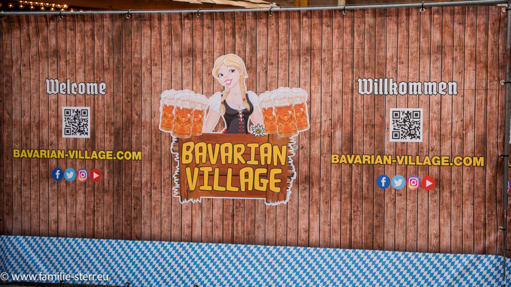 Zaun mit einer Bedienung und vielen Bierkrügen am Rande des Bavarian Village in London