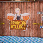 Zaun mit einer Bedienung und vielen Bierkrügen am Rande des Bavarian Village in London