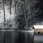 Bootshaus am Ufer des winterlich - ruhigen Alpsees